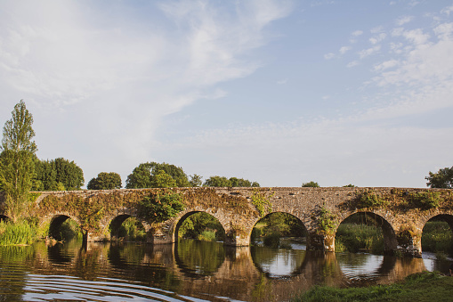 Ancient stone arch bridge in lovely setting at sunset. Medieval stone bridge located in County Cork, Ireland.