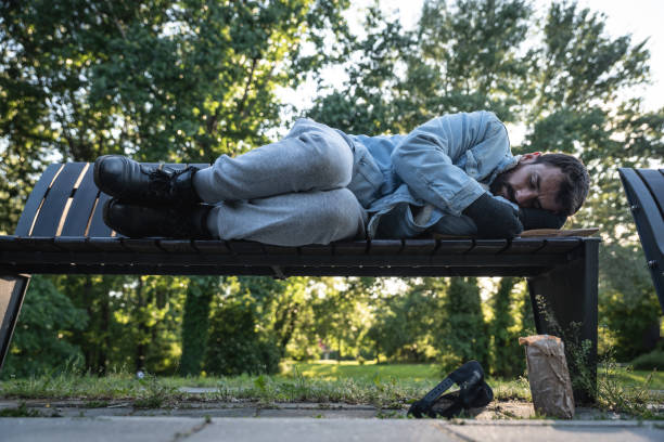 Young hungry despair ill homeless man feeling abandoned and sad sitting outdoors. Jobless sick desperate male need help. Homelessness social issues concept. stock photo