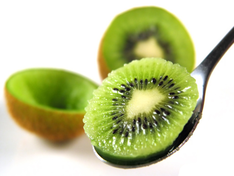 Stock photo showing a close-up view of healthy eating image of a group of Chinese gooseberry (kiwi), one cut in half displaying bright green flesh with ring of black seeds.