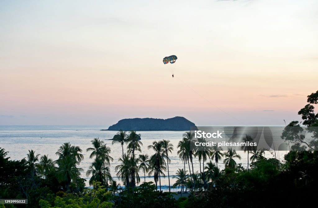 Parasailing over Manuel Antonio at dusk, Costa Rica Sunset silhouettes and bright colours in the sky are created by nature in the tropical climate and tropical rainforest of Costa Rica as the sun sinks below the horizon Costa Rica Stock Photo