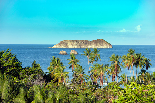 Rocky and rugged dramatic coastline at the shoreline of Manuel Antonio National Park coastline, where waves break over the outcrops to reach the sandy beaches, Costa Rica