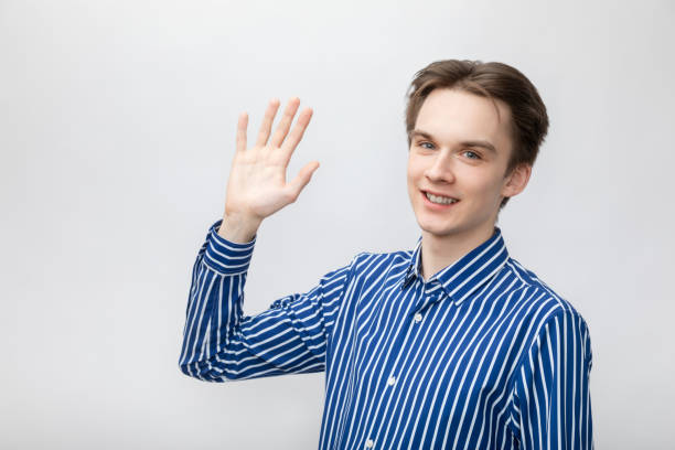 istock Happy young man waving hand studio portrait 1393997184