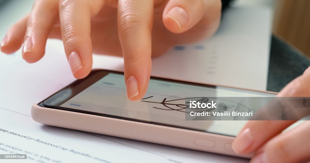 Electronic Signature on smartphone screen. Electronic Signature on smartphone screen with woman hand. Sign Document of Deal at Work in Office Indoors. Write Business Agreement for Entrepreneur. Contract digital signature. Electronic Signature Stock Photo