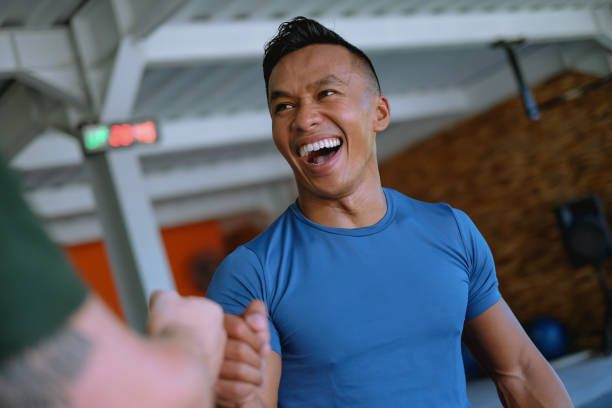 Smiling Indonesian Athlete Giving Fist Bump To His Workout Partner stock photo