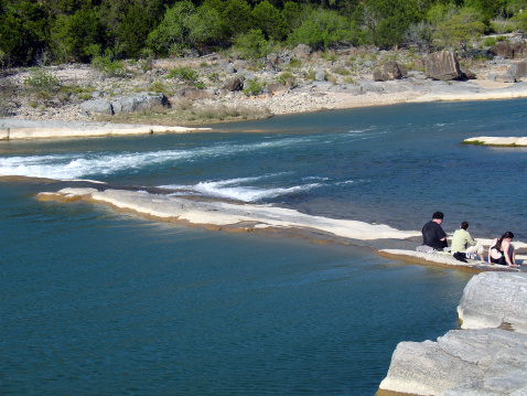 Family with feet in water at Pedernales Falls State Park in central Texas.