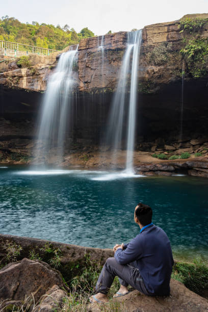 istock young man with waterfall streams falling from mountain top at morning long exposure shot 1394001831