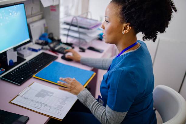 Nurse working at the reception desk in the private clinic Black woman using computer to work as nurse in the private clinic. medical exam stock pictures, royalty-free photos & images