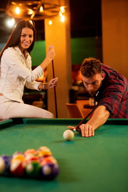 istock Young happy couple enjoying playing billiard on a date in pool hall 1394006332