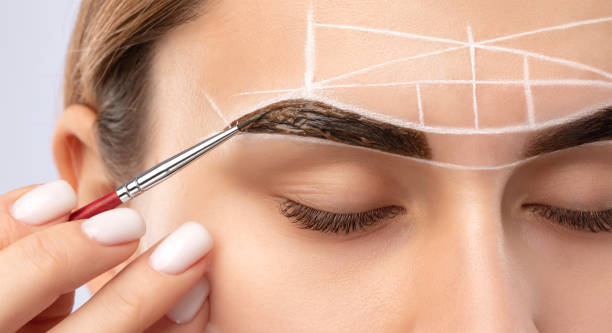 istock Make-up artist makes markings with white pencil for eyebrow and paints eyebrows. Professional makeup and facial care. 1394006989