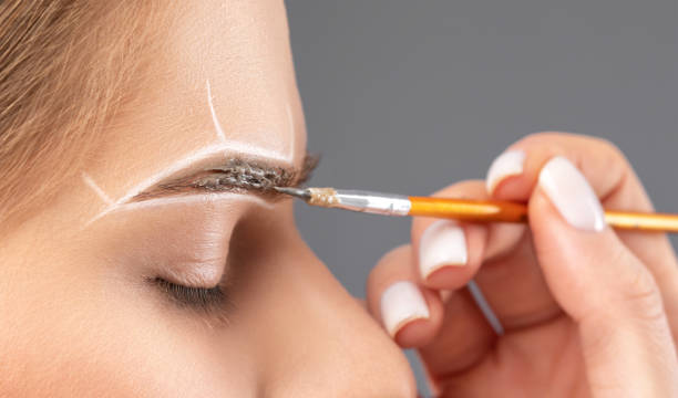 istock Make-up artist makes markings with white pencil for eyebrow and paints eyebrows. Professional makeup and facial care. 1394007006