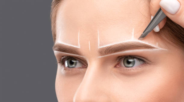 istock Make-up artist makes markings with white pencil for eyebrow and paints eyebrows. Professional makeup and facial care. 1394007012