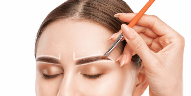 istock Make-up artist makes markings with white pencil for eyebrow and paints eyebrows. Professional makeup and facial care. 1394007062