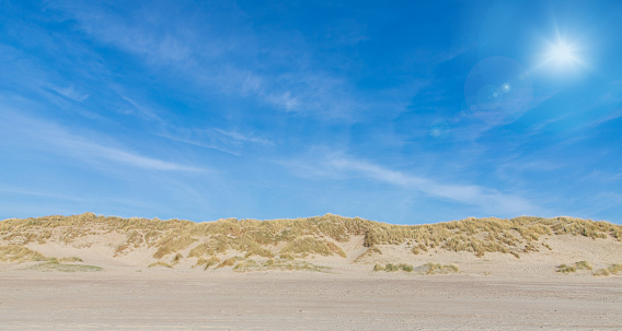 Tranquil scenic view of sand dune mountain and grassy landscape against clear blue sky at Lønstrup, Denmark during sunny day