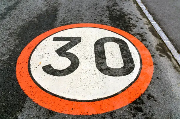 traffic sign of a speed limit of 30 km/h, painted on an asphalted roadway