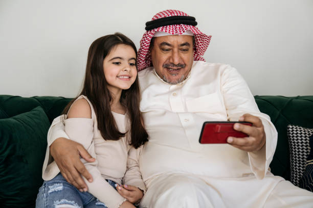 saudischer mann und enkelin nutzen smartphone zusammen - naher und mittlerer osten stock-fotos und bilder