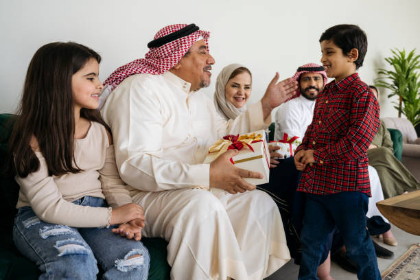 famiglia saudita che celebra eid al-fitr e si scambia regali - saudi arabia child ramadan offspring foto e immagini stock
