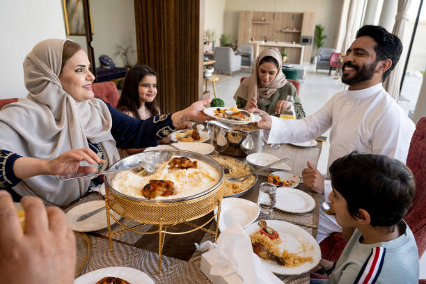 mulher saudita madura servindo saleeg para membro da família - saudi arabia child ramadan offspring - fotografias e filmes do acervo