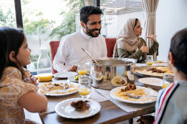 homem saudita adulto médio em prato traço rindo durante a refeição do meio-dia - saudi arabia child ramadan offspring - fotografias e filmes do acervo