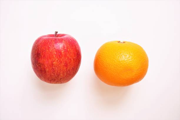 istock One red apple and  oranges lined up on a white background 1394011794