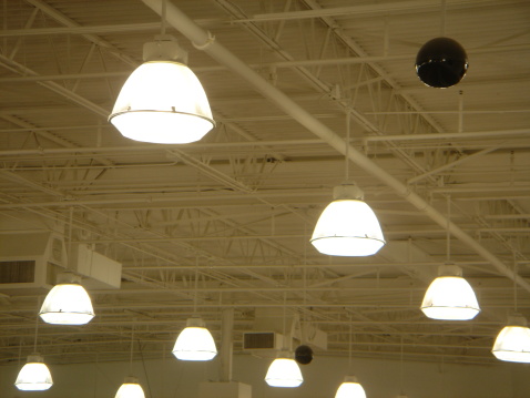 Bright metal halide lamps on the warehouse ceiling with security camera.