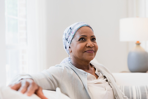 The elderly woman with cancer looks off into the distance and sits alone to contemplate upcoming decisions.