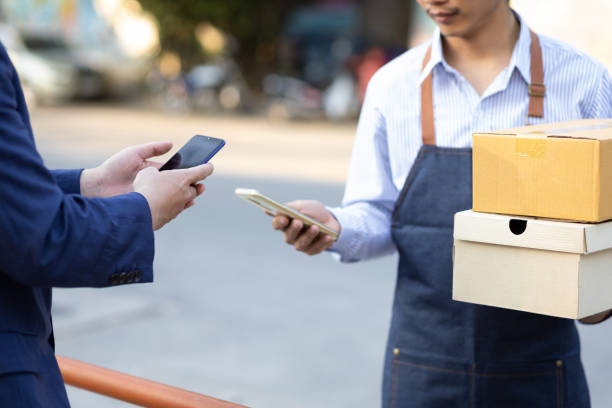 istock Man uses mobile phone to confirm payment before picking up parcel from delivery man. 1394016623