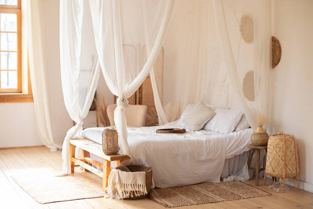 istock hygge decor at home. interior white bedroom in boho  style with coffe table,straw lamp and comfortable bed with pillows, copy space. bed with flowing white curtains. Cozy scandinavian decoration room 1394016878