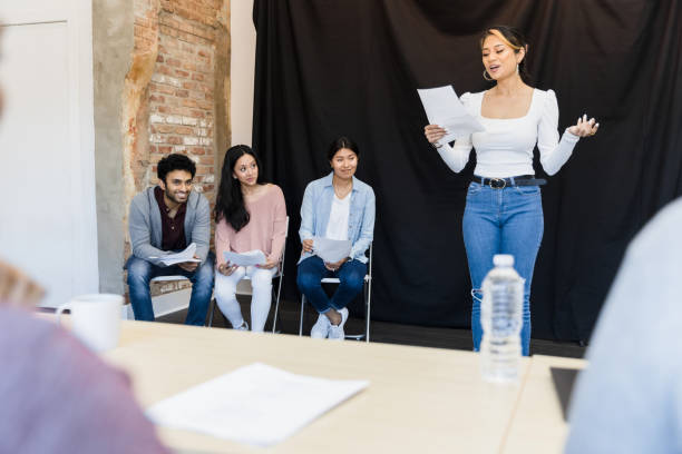 giovane donna presenta il monologo a giudici irriconoscibili in primo piano - audition foto e immagini stock