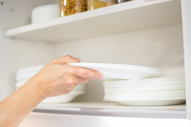 istock Person's hand leaves a plate in a cupboard next to the other kitchen utensils. 1394017942