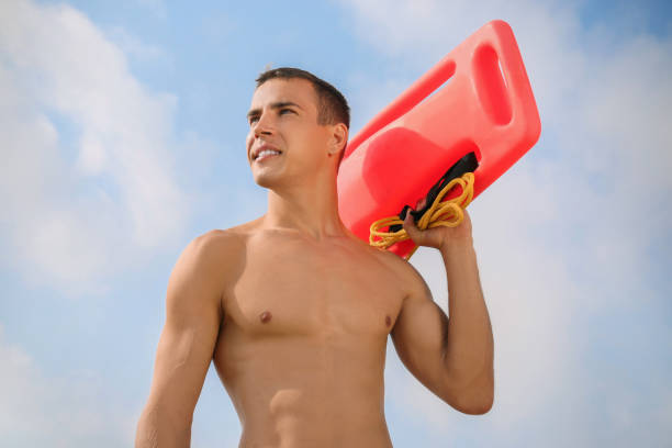 istock Handsome lifeguard with life buoy against blue sky 1394018011