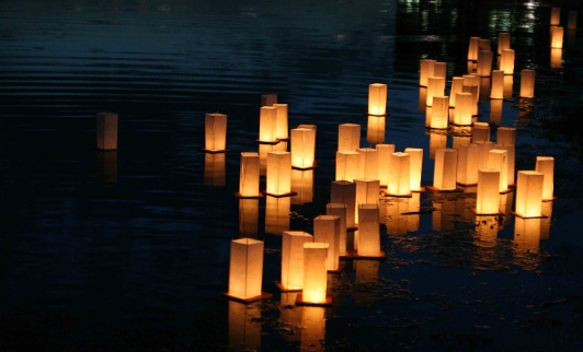 Lanterns floating on a lake at dusk.