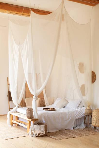 istock interior white bedroom in boho  style with coffe table,straw lamp and comfortable bed with pillows, copy space. bed with flowing white curtains. Cozy scandinavian decoration room. hygge decor at home 1394018798