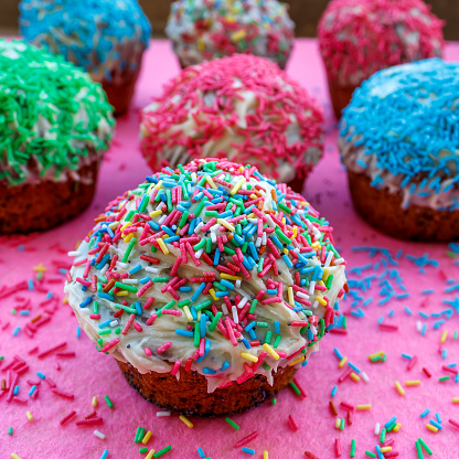 Close-up of homemade cupcakes decorated with white frosting and multi colored sugar sprinkles