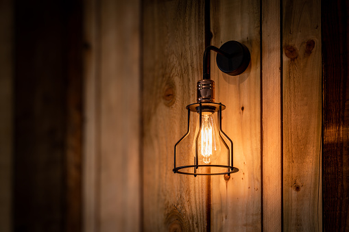 Trendy filament style LED bulb on a rough cut wood wall