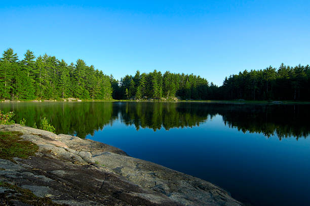 Lake Reflections Out in the wild and overlooking a lake with tree reflections while standing on a rocky cliff in northern Canada. northern ontario stock pictures, royalty-free photos & images