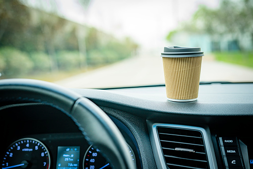 Close up view of disposable coffee cup on car dashboard. High resolution 42Mp outdoors digital capture taken with SONY A7rII and Zeiss Batis 40mm F2.0 CF lens
