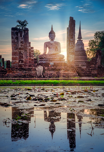 Big Buddha at sunset in Wat Mahathat temple, Sukhothai Historical Park, Thailand.