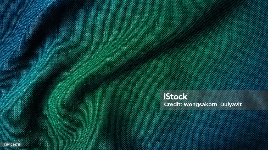 close up texture of creased fabric. gradient in green and blue color tone, woolen fabric. wavy cloth background showing fiber detail. gradient drapery background with beautiful, light and shadow. Plaid Stock Photo