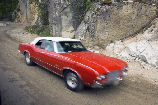 gorgeously restored vintage sportscar speeds past on a mountain pass - intentional motion blur