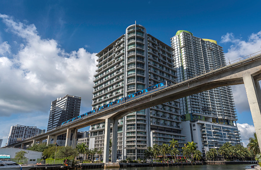 Miami, USA - April 27, 2022: View of downtown Miami and the Miami River. The image shows Metrorail service crossing the ramp over the Miami River surrounded by modern skyscrapers. Metrorail is a commuter rail system operated by Miami-Dade Transit in Miami.
