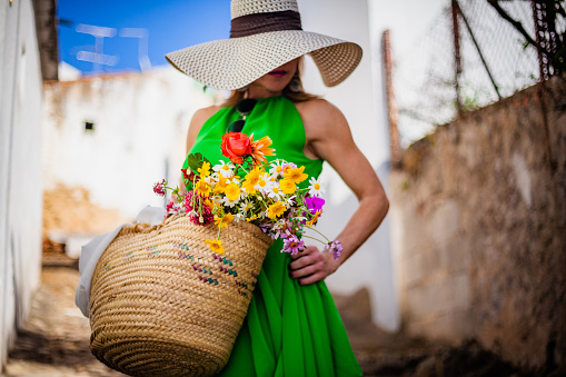 elegant spanish woman walking on the street with a basket of flowers in a rural village in the Algarve