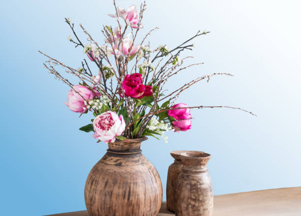 istock Wild peony bouquet in vase against blue background. 1394044546
