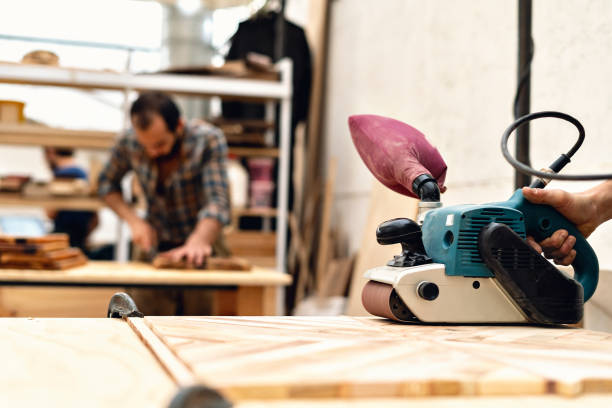 istock Carpenter sanding a piece of wood while his partner does his work. 1394047149