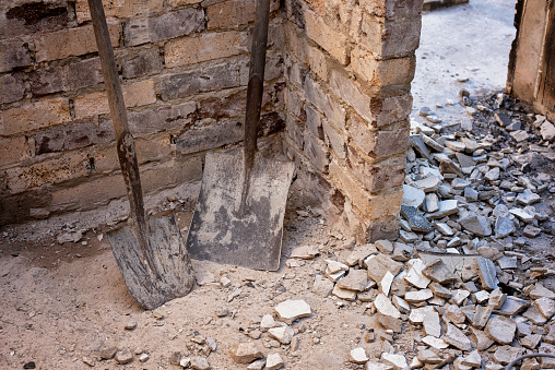 Two Shovels in a Room being Renovated with Broken Bricks, Dust and Rubble