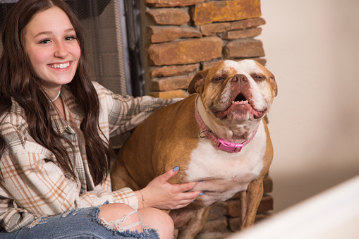 Teenage girl and her pet English Bulldog.  They share the sofa and affection for each other.