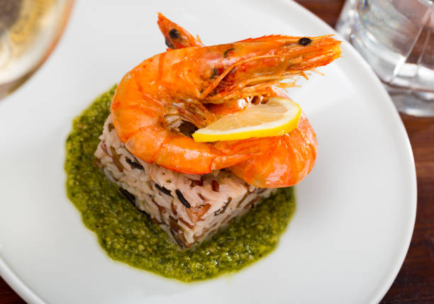 Baked tiger shrimps on rice pillow with lemon and sauce