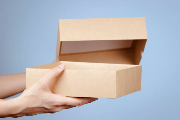 istock Female hands opening brown cardboard box on light blue background. Mockup parcel box. Present, packaging, shopping, delivery concept 1394052121