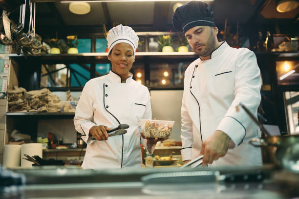 istock Multi-ethnic professional cooks cooperating while preparing food in the kitchen. 1394053596