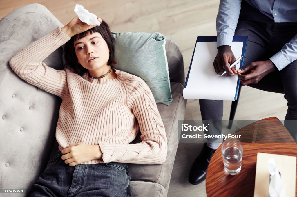 Depressed Woman in Office of Therapist Depressed young woman lying on sofa in office of her therapist and talking about her struggles, view from above Mental Health Professional Stock Photo