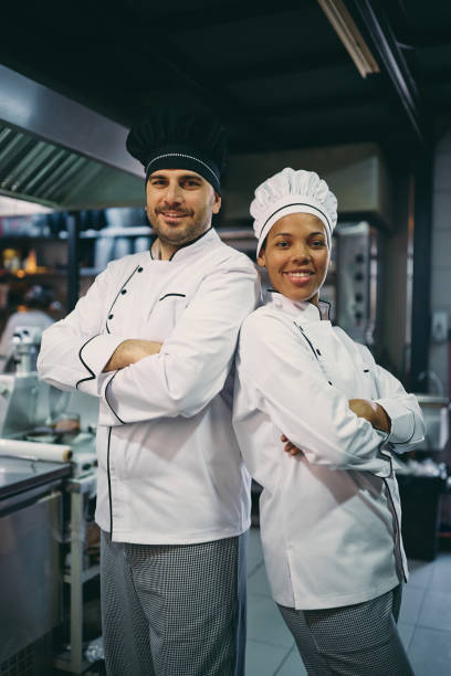 istock Happy professional chefs standing with crossed arms and looking at camera. 1394053786